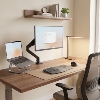 Bureau à domicile moderne, épuré et ergonomique, avec MacBook sur support, moniteur articulé, et étagère décorative minimaliste.