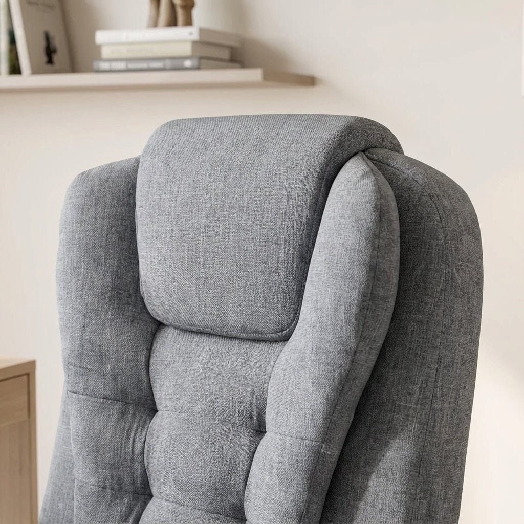 Gros plan sur l'appui-tête et le dossier supérieur d'un fauteuil de bureau rembourré en tissu gris, montrant la couture matelassée et une étagère avec des livres flous en arrière-plan.