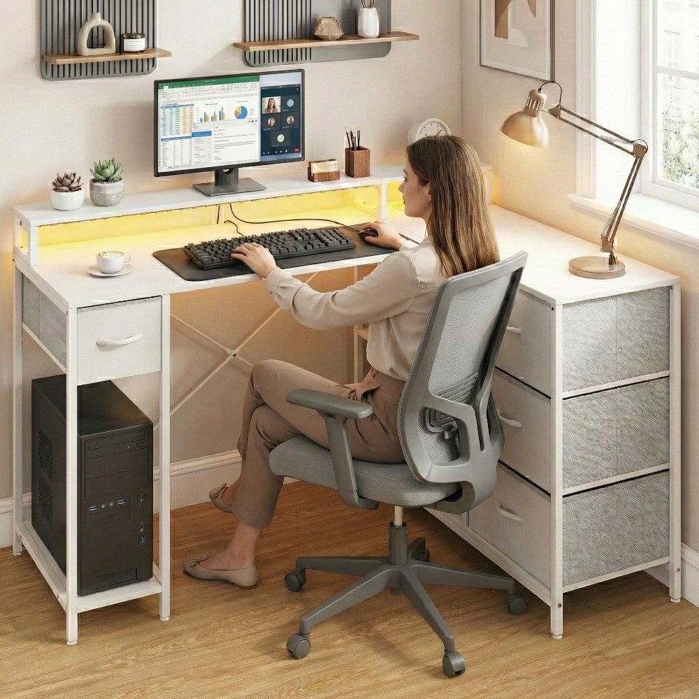 Femme travaillant sur le bureau d'angle blanc ZENITH, illustrant l'ergonomie de la rehausse écran et l'espace de travail.