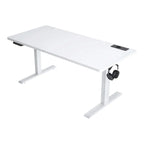 Un rendu de studio moderne et propre d'un bureau assis-debout électrique réglable en hauteur (140-160 cm de largeur), montrant un cadre en acier blanc et un plateau en chêne clair, positionné à mi-hauteur. Panneau de commande numérique à bouton-poussoir sur le bord avant. Ordinateur portable et tasse sur le plateau pour l'échelle. Fond blanc isolé.