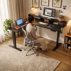 Une femme assise travaillant confortablement sur le bureau d'angle assis-debout Kova Pro dans un intérieur chaleureux.