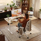 Femme installée devant ses écrans sur le bureau d'angle ergonomique Kinetik-L dans un décor de bureau cosy et chaleureux.