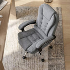 Fauteuil de bureau ergonomique gris en tissu avec base chromée, accoudoirs rembourrés et dossier haut, dans un bureau moderne avec un grand moniteur incurvé, un bureau en bois clair et une fenêtre lumineuse.