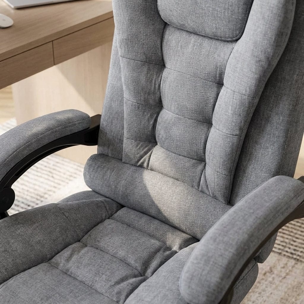 Fauteuil de bureau ergonomique en tissu maillé gris, rembourré et matelassé, avec soutien lombaire intégré et accoudoirs, placé devant un bureau en bois clair.