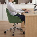 Homme travaillant sur un bureau en bois avec une chaise de bureau design verte.