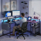 Un homme travaillant sur le bureau d'angle en configuration L avec double écran, éclairage LED bleu et PC intégré.