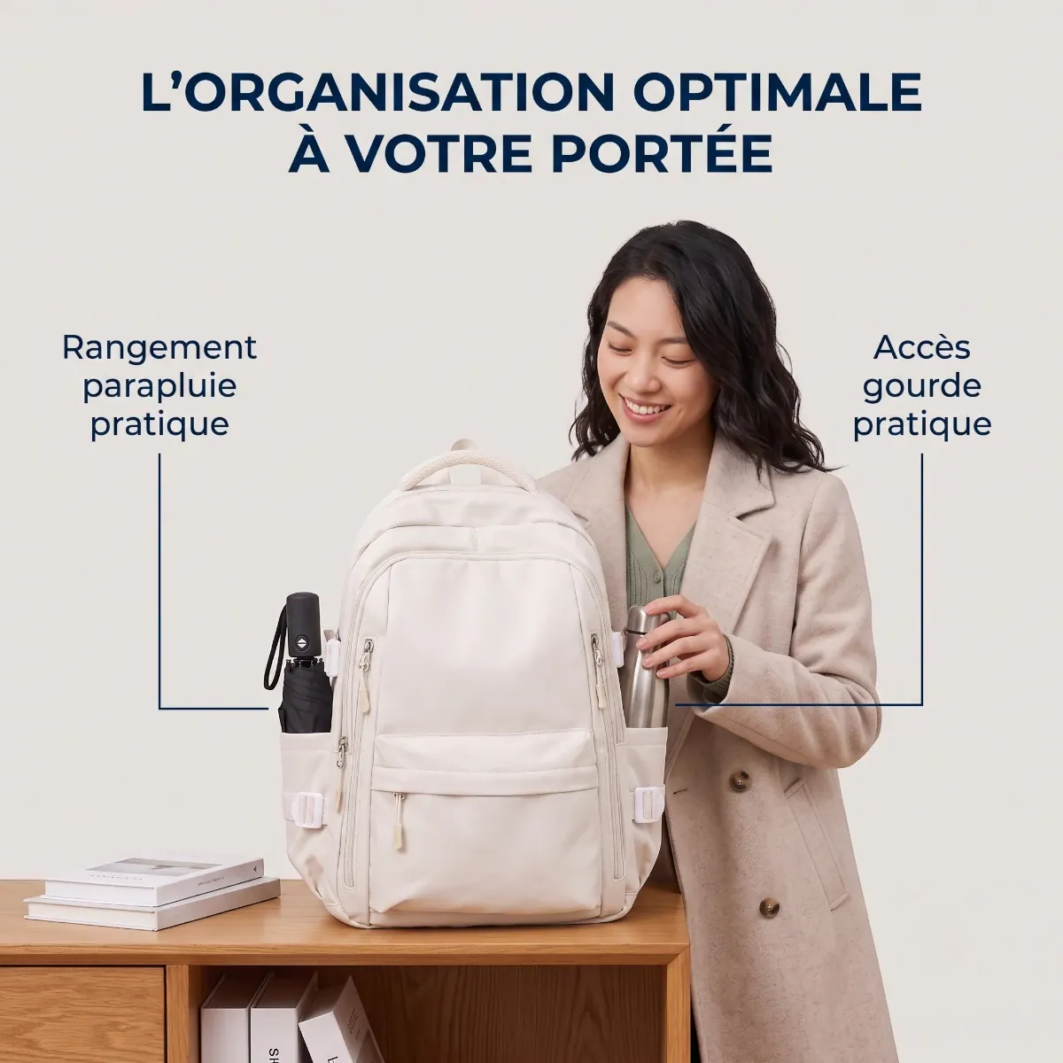 Image de mise en scène carrée du sac à dos multifunctional Irisia en crème, montrant la femme organisée et heureuse de l'image de référence. Le sac est sur une table en bois et ses poches latérales sont mises en évidence. Une gourde en métal est dans une poche et un parapluie compact est dans l'autre. Le titre en français dit: 'L'ORGANISATION OPTIMALE À VOTRE PORTÉE'. La police est Sans Serif bleu marine sur un fond crème.