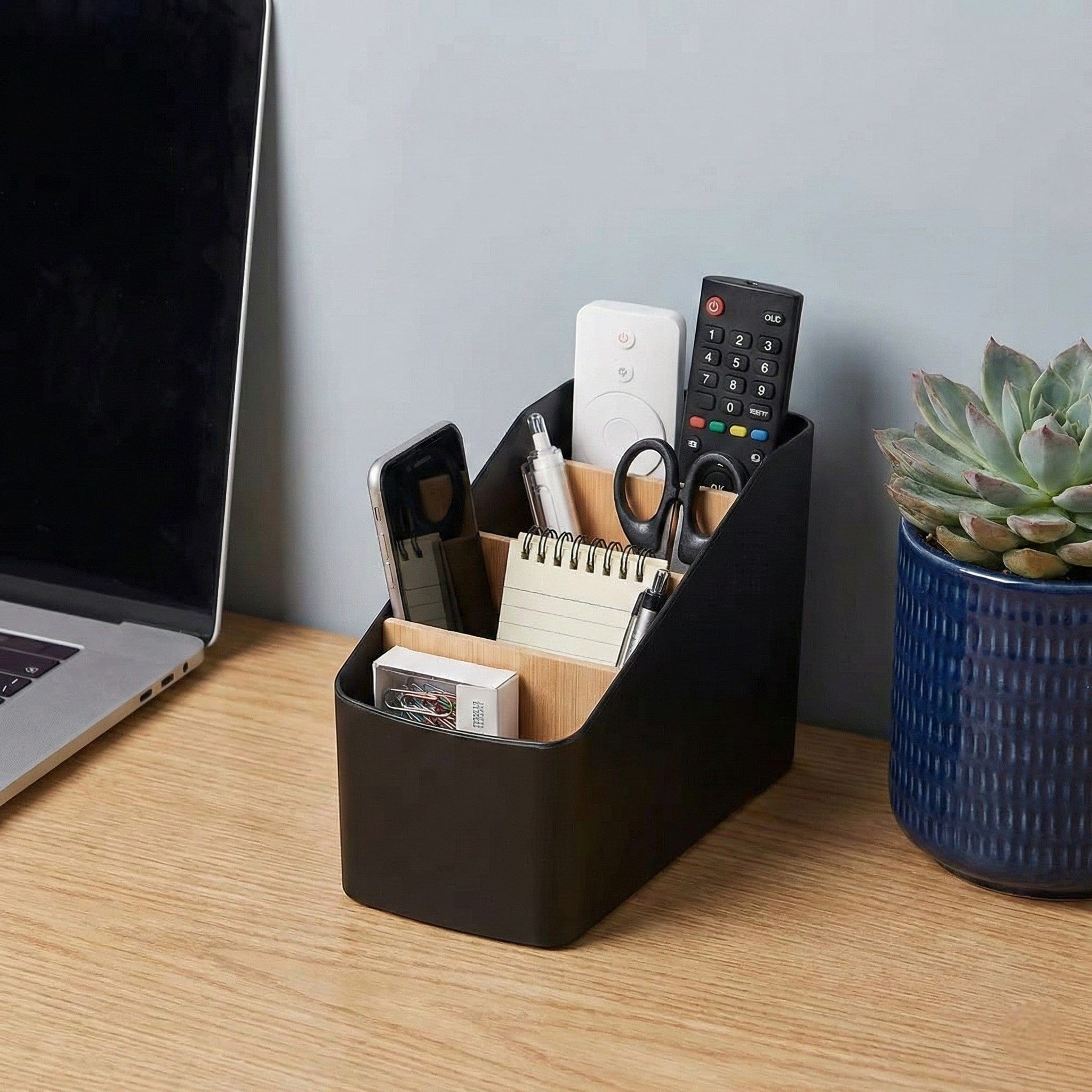 Organisateur de bureau SKALA utilisé pour ranger télécommandes, stylos et téléphone.