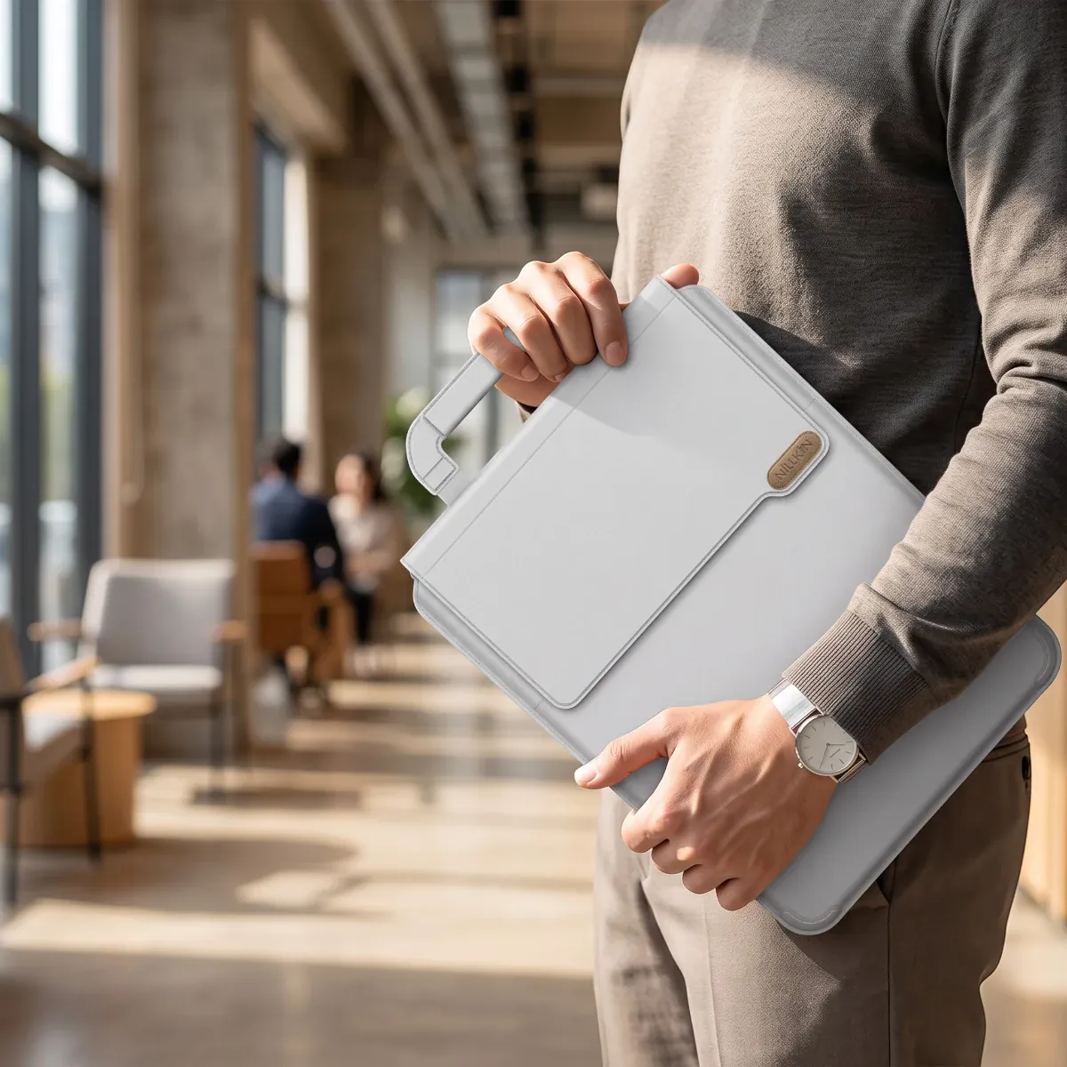 Homme portant la pochette ordinateur MorphoDesk gris nuage à la main avec sa poignée rétractable dans un espace de travail nomade.