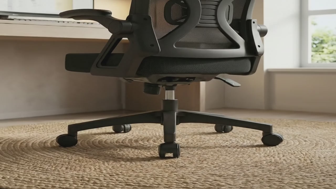 Gros plan sur une chaise de bureau ergonomique noire en maille, posée sur un tapis rond en jute, qui pivote. Un homme s'assoit, ajustant sa posture. Le fauteuil est bien rembourré et possède un support lombaire ajustable, des accoudoirs relevables et un appui-tête réglable. L'homme est assis confortablement à son bureau en bois clair et commence à travailler sur son ordinateur. La vidéo présente la facilité d'utilisation et le confort de la chaise Authmic.