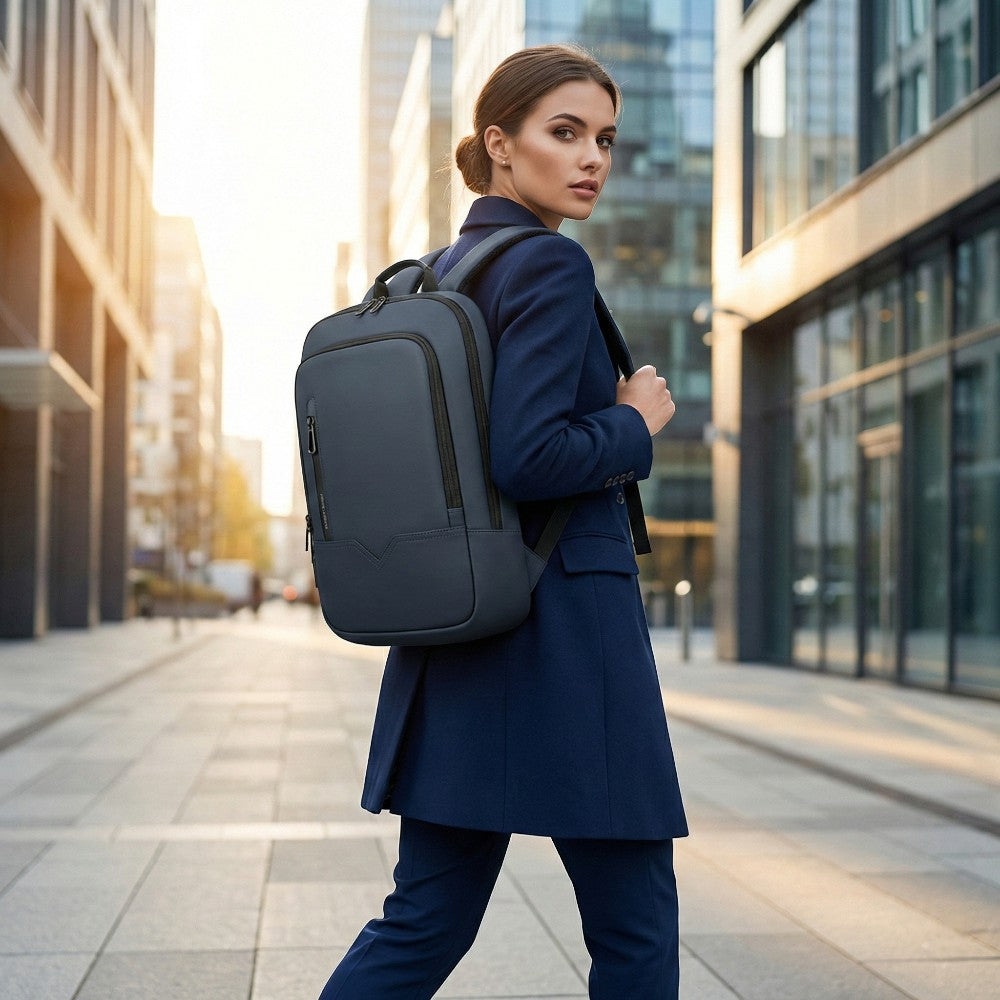 Femme d'affaires portant le sac à dos HK Shadow-Slim bleu marine dans un quartier d'affaires moderne, look professionnel et fin.