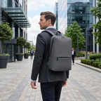 Homme portant le Sac à dos ordinateur homme Classic Business V2 gris dans un quartier d'affaires moderne.