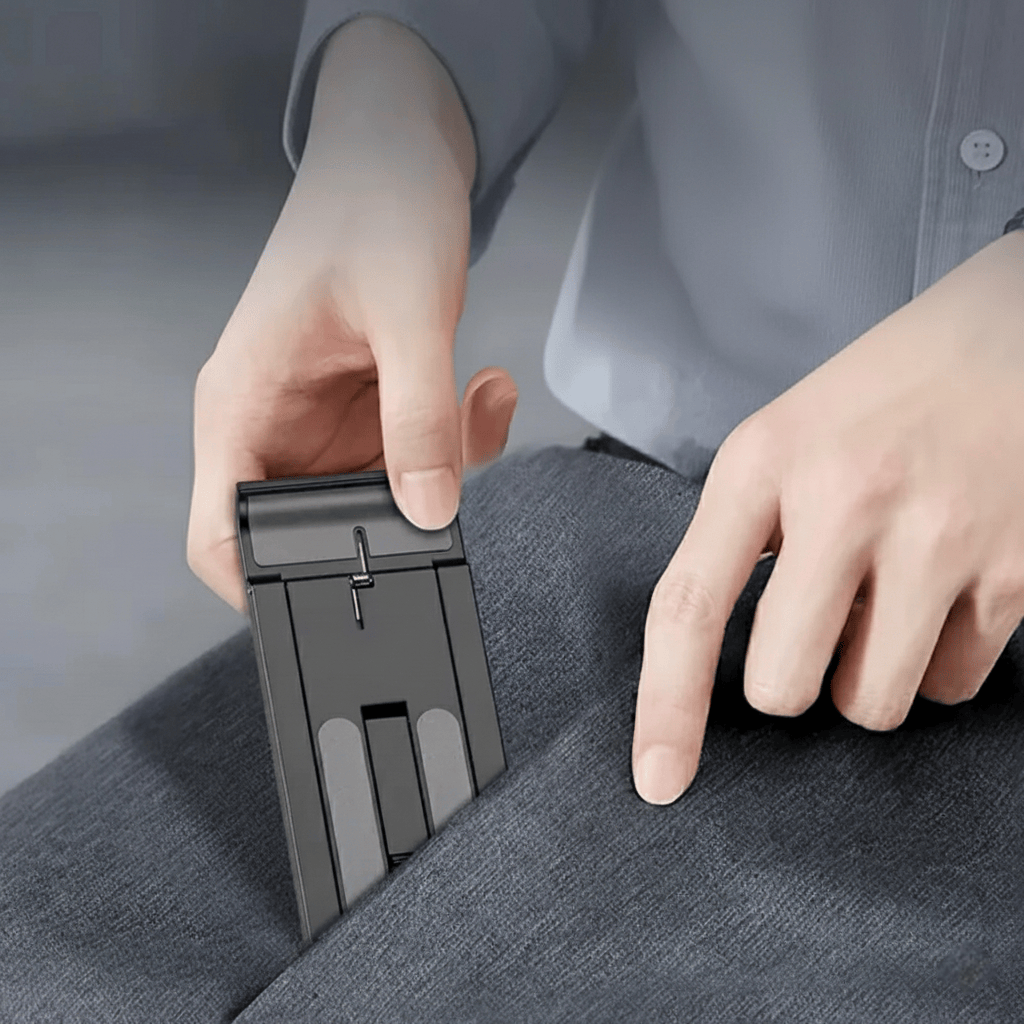 Support smartphone pliable ultra-compact noir tenu en main montrant sa portabilité, idéal pour voyage et bureau nomade