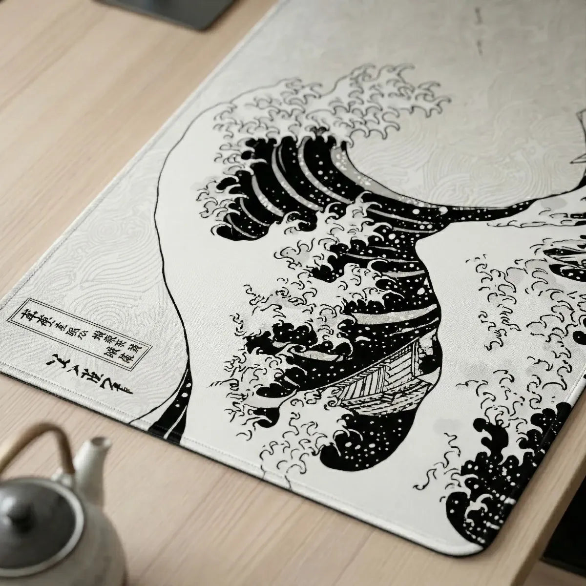 Gros plan détaillé en vue 3/4 du tapis de souris Kanto Flow Edition montrant la finesse du micro-tissage haute densité et la précision de l'imprimé "Grande Vague" monochrome sur un bureau en bois clair.