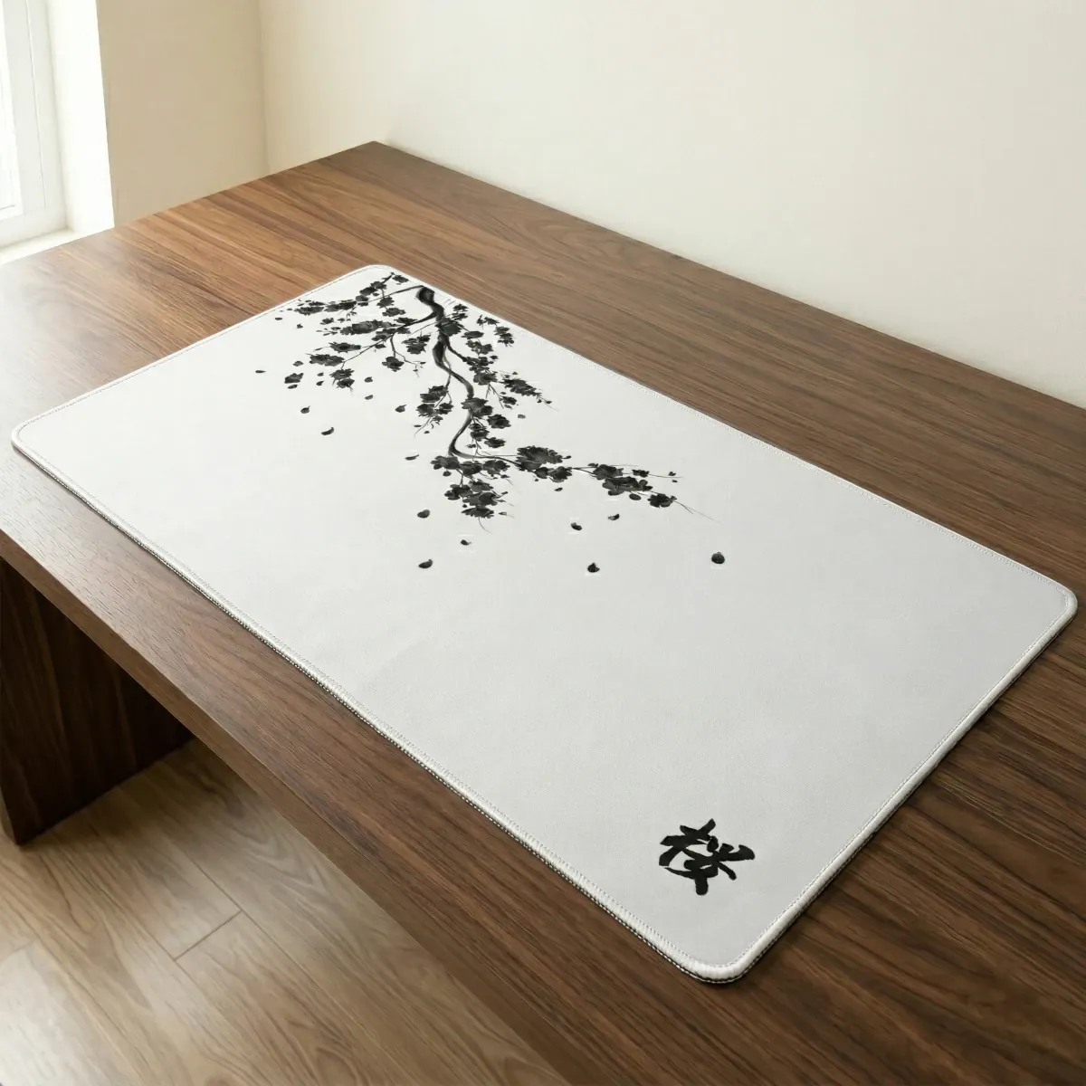 Vue en gros plan et en plongée du tapis de souris Sakura Daylight XXL au micro-tissage haute densité, reposant sur un bureau en noyer foncé. Le design épuré présente un motif calligraphique de branche de cerisier en encre de Chine noire qui s'étend sur la surface, avec le kanji japonais 'Sakura' dans le coin inférieur droit. Une image de design pur pour sérénité et précision.