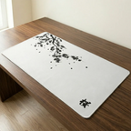 Vue en gros plan et en plongée du tapis de souris Sakura Daylight XXL au micro-tissage haute densité, reposant sur un bureau en noyer foncé. Le design épuré présente un motif calligraphique de branche de cerisier en encre de Chine noire qui s'étend sur la surface, avec le kanji japonais 'Sakura' dans le coin inférieur droit. Une image de design pur pour sérénité et précision.