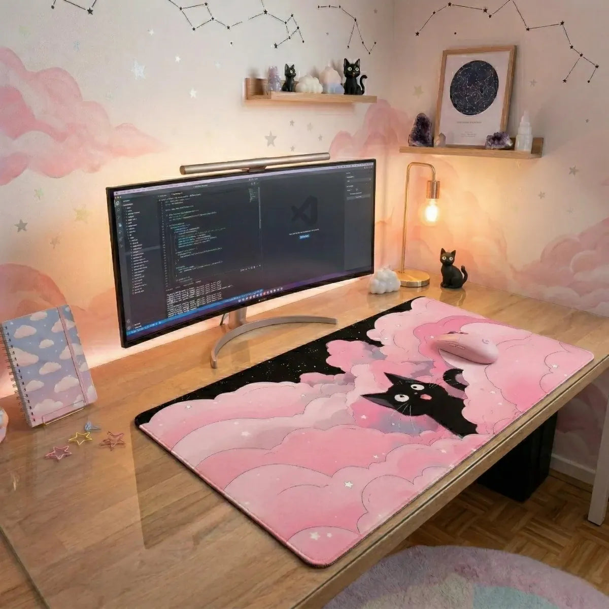 Texte alt : Photo de produit montrant un grand tapis de souris rose pastel avec un chat noir mignon (type Jiji) émergeant de nuages moelleux. Le tapis est intégré dans un setup de bureau Kawaii complet avec clavier, souris, écran ultra-wide et décorations célestes.