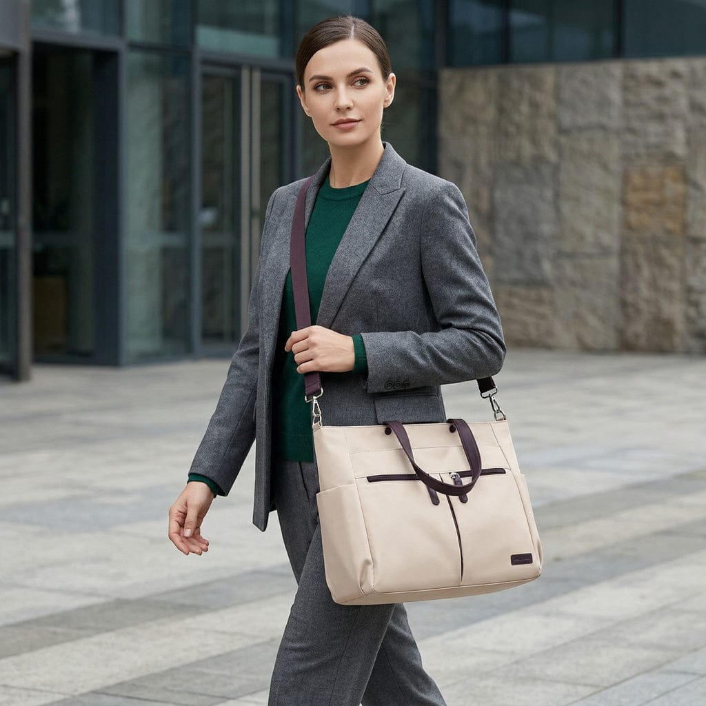 Mannequin femme portant le tote bag ordinateur L'Aérienne 15" en bandoulière à l'extérieur, en marchant dans un décor urbain moderne.